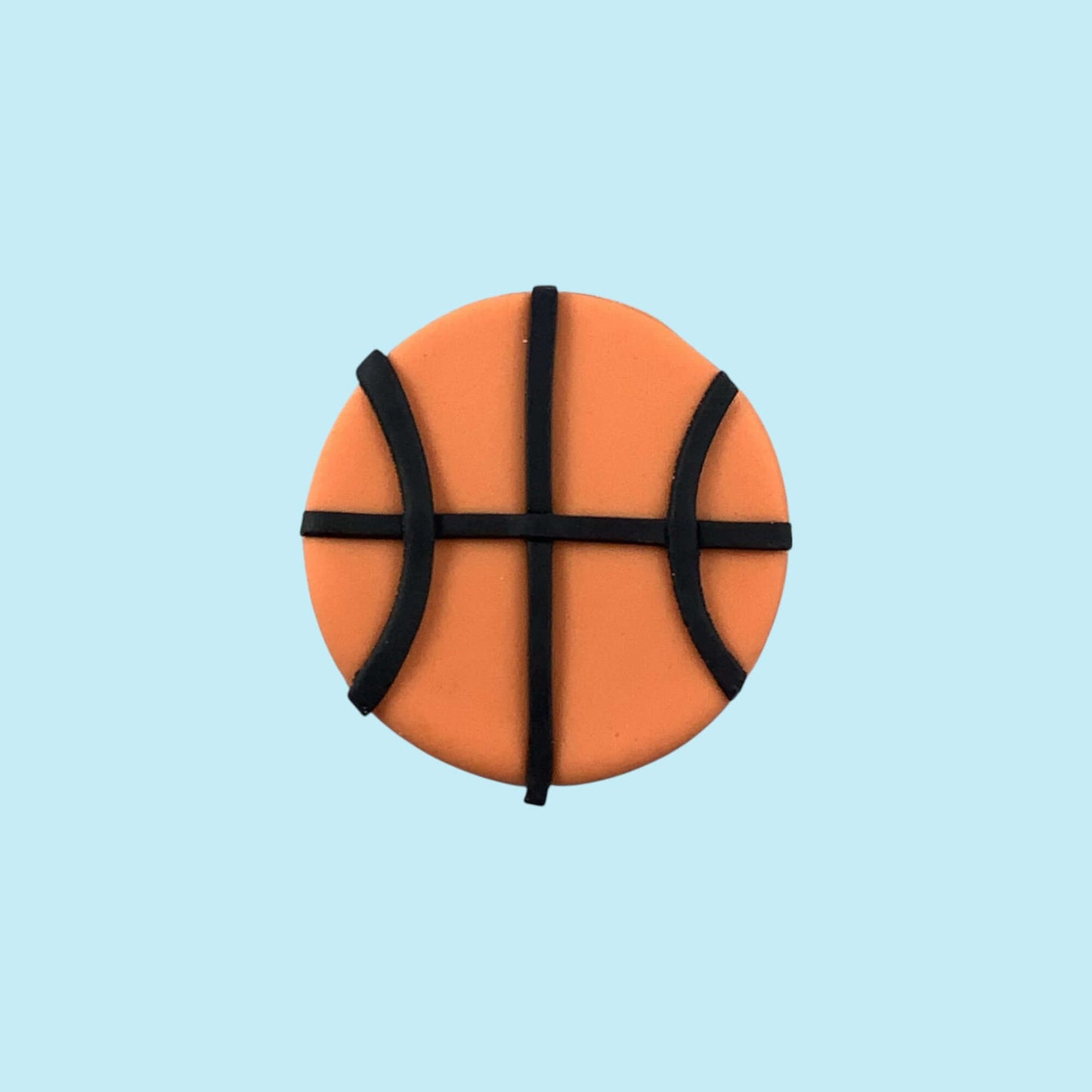 Round orange cupcake topper resembling a basketball on a light blue background