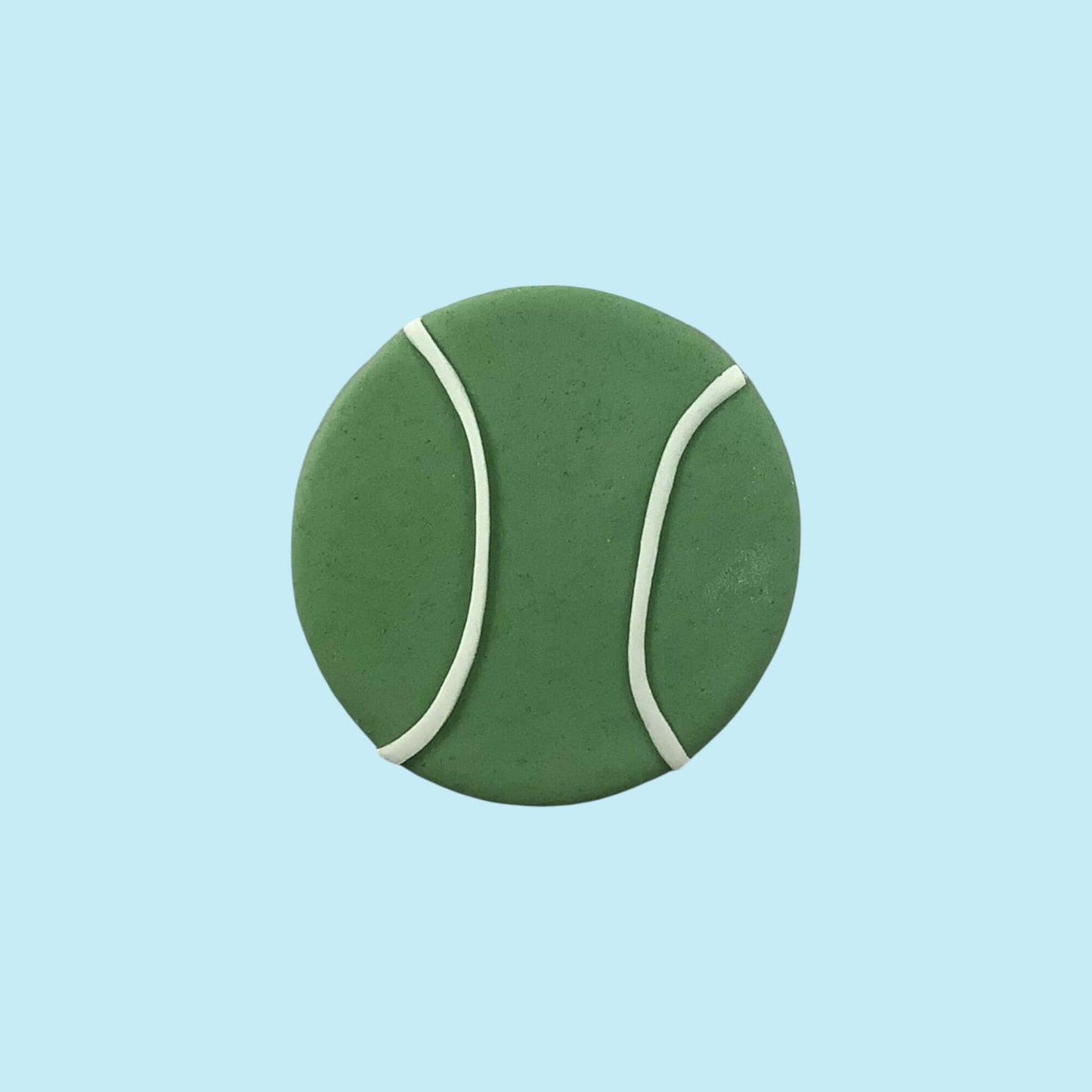 Green tennis ball with white seams on a light blue background