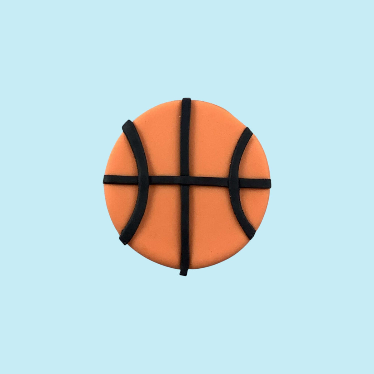 Round orange cupcake topper resembling a basketball on a light blue background